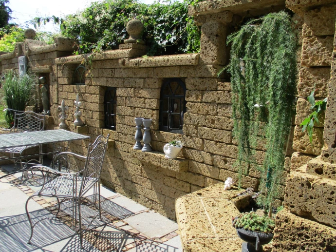 Tuffmauer mit Nischen und bepflanztem Gartenbereich