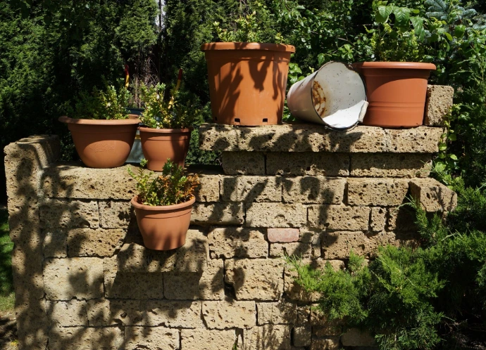 Pflanzgefäße und Gartendekoration auf einer Tuffmauer