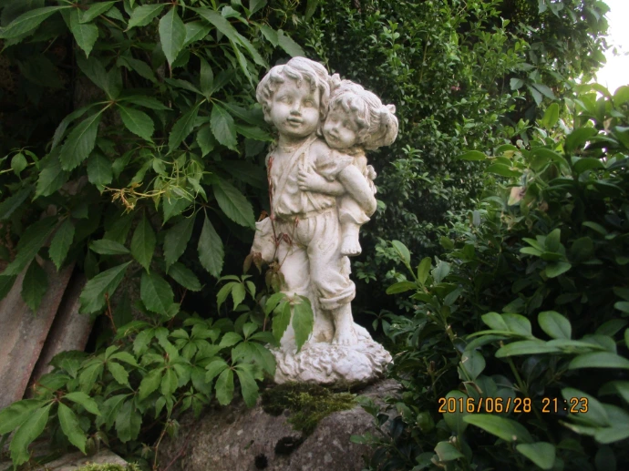 Blumenfigur zwischen grünen Gartenpflanzen
