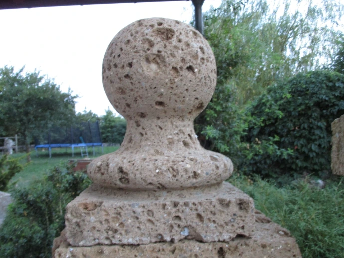 Kugelförmiger Natursteinaufsatz auf einem Gartenpfeiler